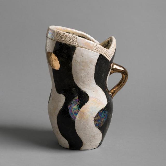 a ceramic pitcher in black and white with golden details.