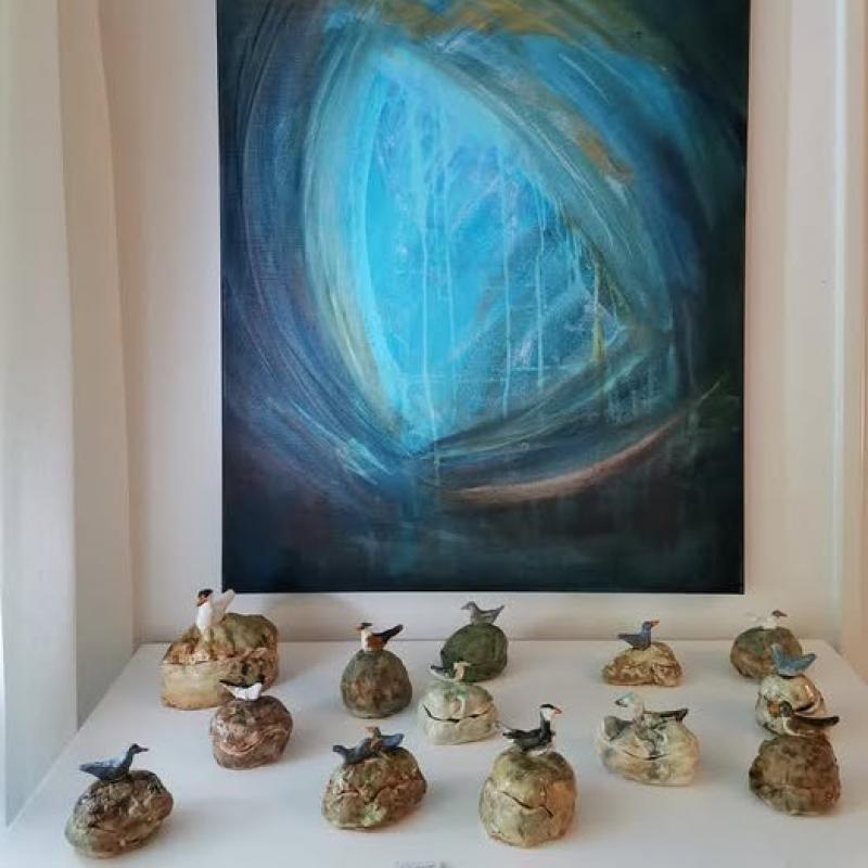 Siipi, akryyli 80 x 60 cm 2024. Edessä keraamisia linturasioita.