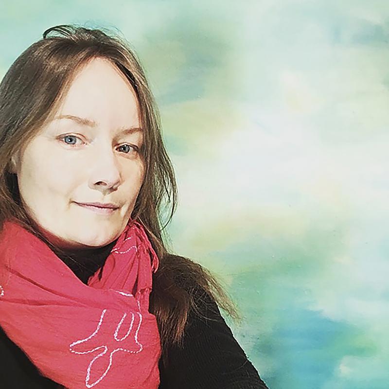 Marjo Yli-Antola, taustalla öljymaalaus Läpikuultavan kirkasta.