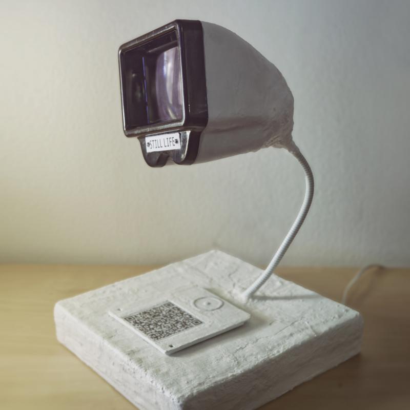 Titel/Nimike/Title: PORTAL
Storlek/koko/size: 30x30x40 cm
Gips, 2x2 dia projektor med diskett och QR kod, Skulptur
Kipsi, 2x2 dia katselulaite sekä korppu QR koodilla, Veistos
Plaster of Paris, 2x2 dia viewer and floppy disk with QR code,  Sculpture