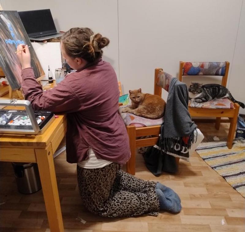 Amanda Nylund i sin hemma-ateljé med två av katterna