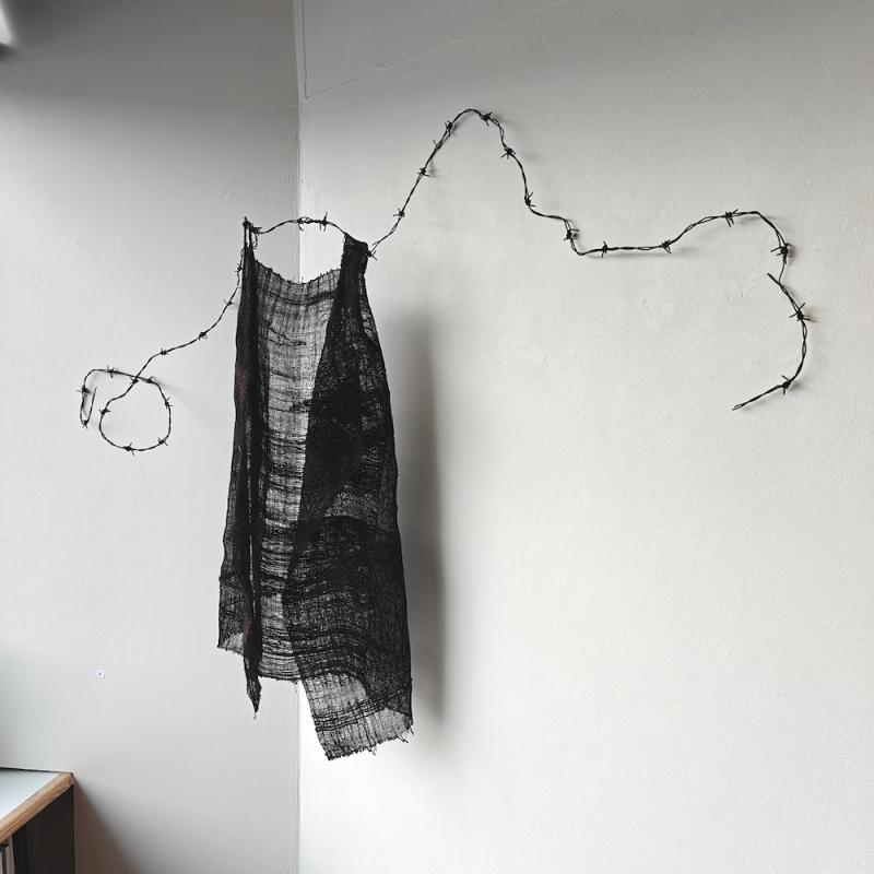 Kerttu Ahlholm, Maatumismekko, kudottu tekstiiliveistos luonnonkuitulangoista ja piikkilangasta, 150 cm x 110 cm x 40 cm, 2025