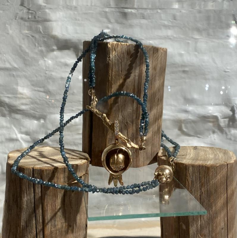 Granatäpple i guld med gröna rådiamantstenar.