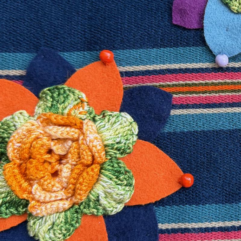 "Blommor från Keuruu". Detalj av en väska. Dräkttyg från Keuruu. "Keuruun kukat".  Koristeltu laukku, yksityiskohta, Keuruun kansallispukukangas.  "Flowers from Keuruu", detail of a bag. Mirka Laine-Pietilä, 30x35 cm. 2026